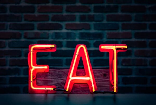 Neon sign illuminating the letters EAT, symbolizing the SEO principles of Expertise, Authority, and Trustworthiness.