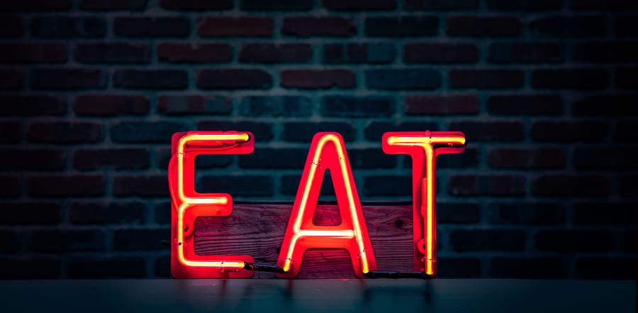 Neon sign illuminating the letters EAT, symbolizing the SEO principles of Expertise, Authority, and Trustworthiness.